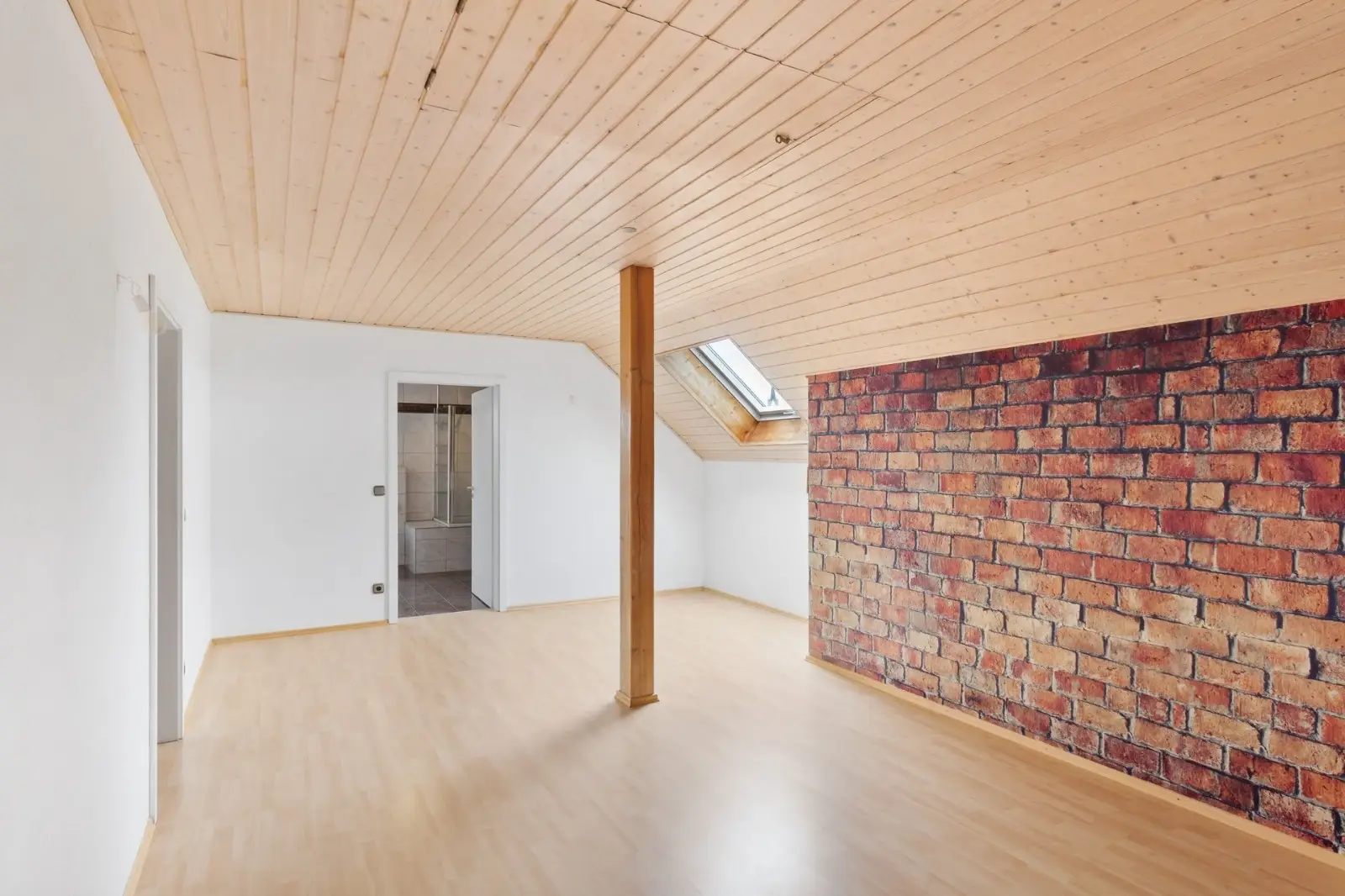 Ausgebautes Dachgeschoss mit Holzdecke, Dachfenster und Ziegelwand